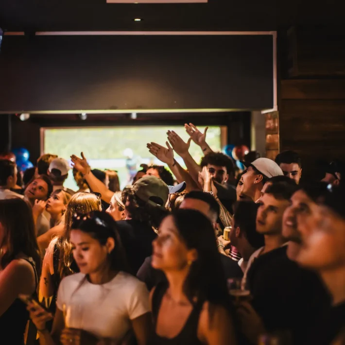Packed Belushi's sports bar with big screens showing the World Cup live, a diverse crowd of international football fans generating the electric atmosphere that makes watching live football at Belushi's unmissable