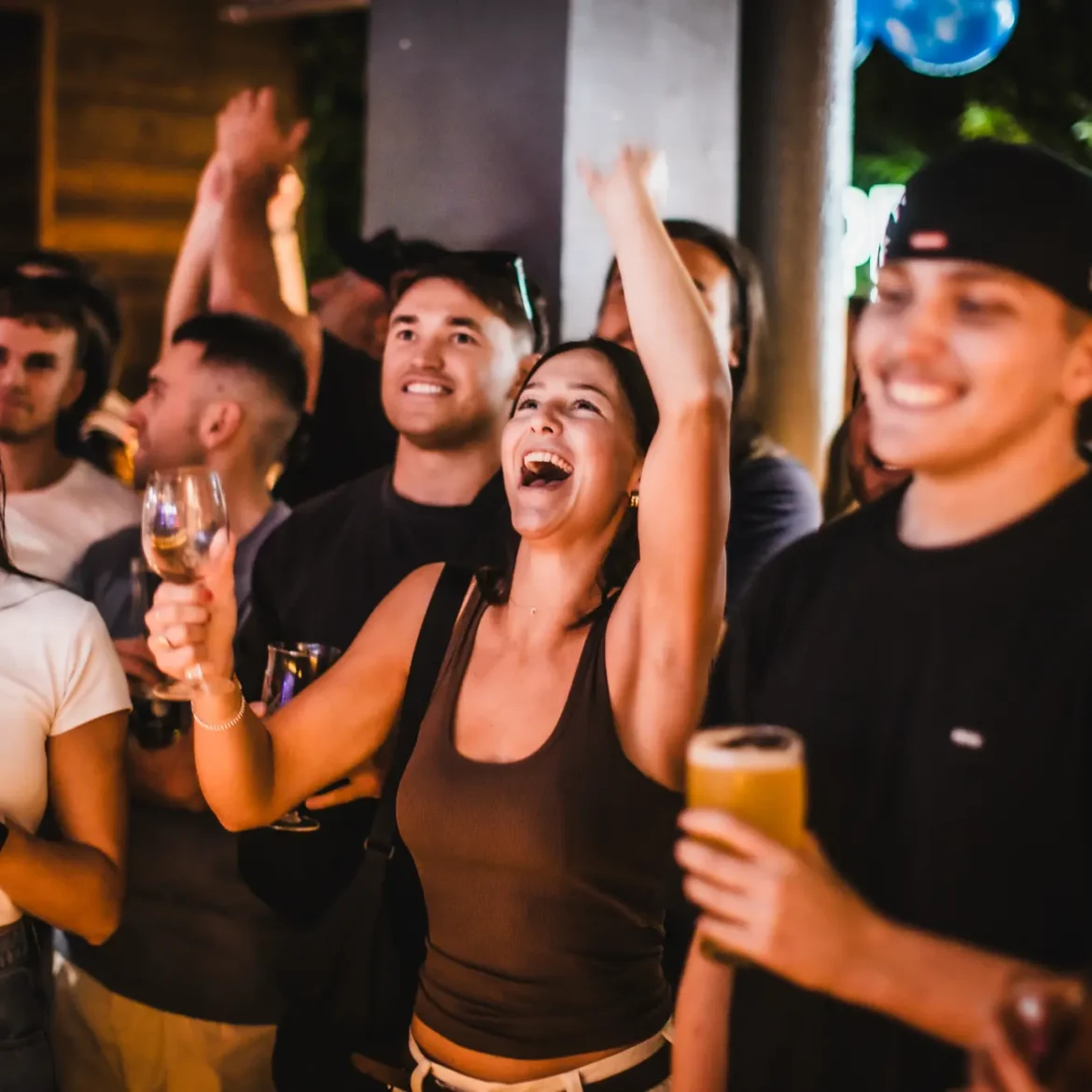 Fans celebrating a World Cup result at Belushi's sports bar at night, craft beers and cocktails in hand as the electric match day atmosphere carries on into the evening